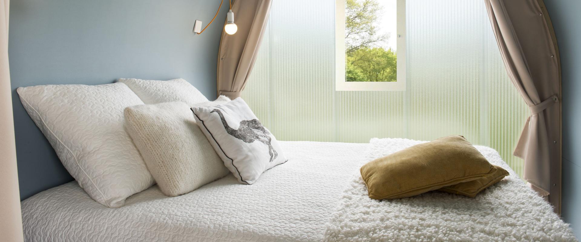 Camera da letto accogliente con cuscini bianchi e finestra luminosa.