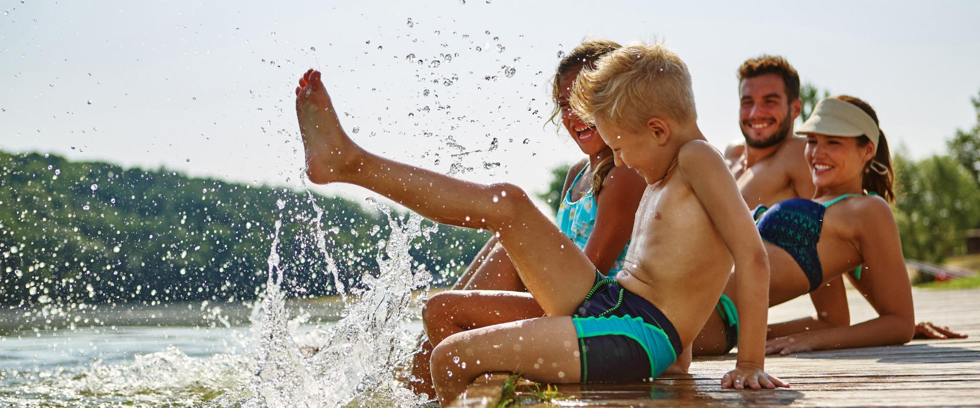 Famiglia si diverte sul pontile, spruzzando acqua in una giornata estiva.