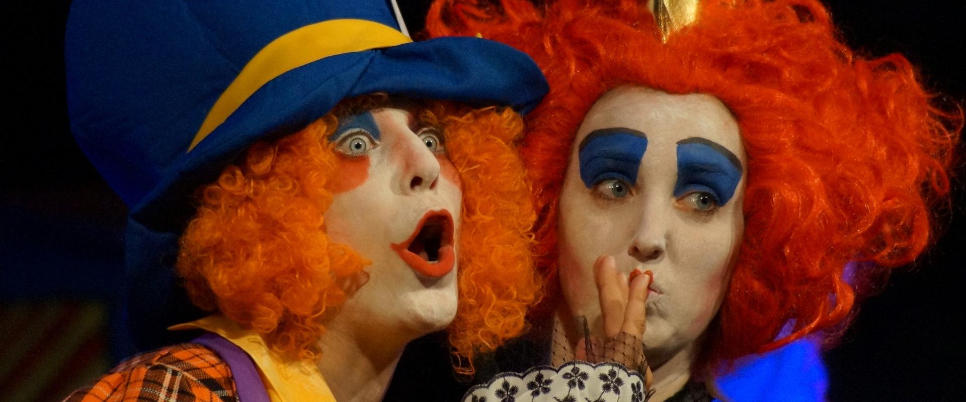 Due clown con parrucche rosse e trucco colorato, esprimono sorpresa e curiosità.