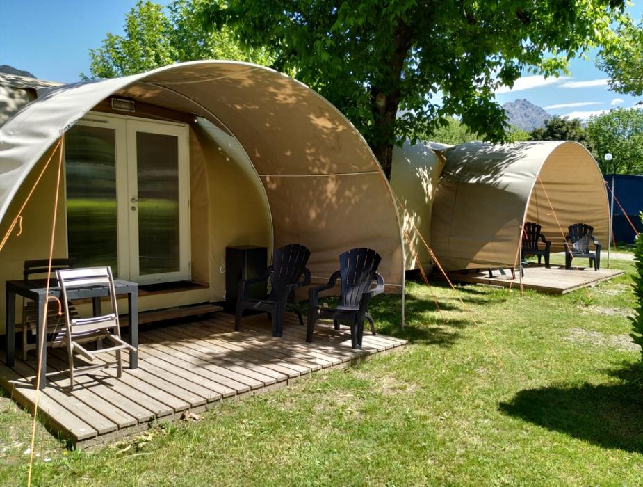 Tende moderne con terrazza in legno immerse nel verde, ideale per campeggio.