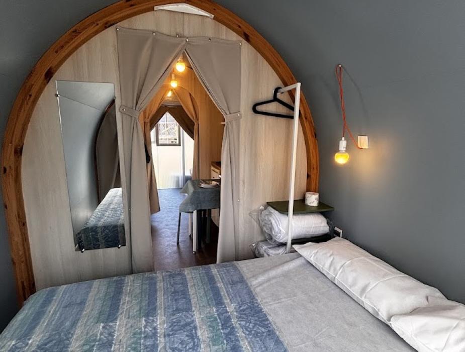 Camera accogliente con letto bianco, finestra e luci sospese, vista sul verde.