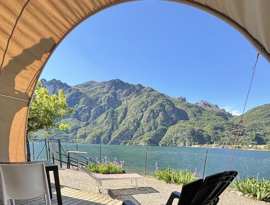 Tavolo apparecchiato per due, con cuscini bianchi su seduta arancione.