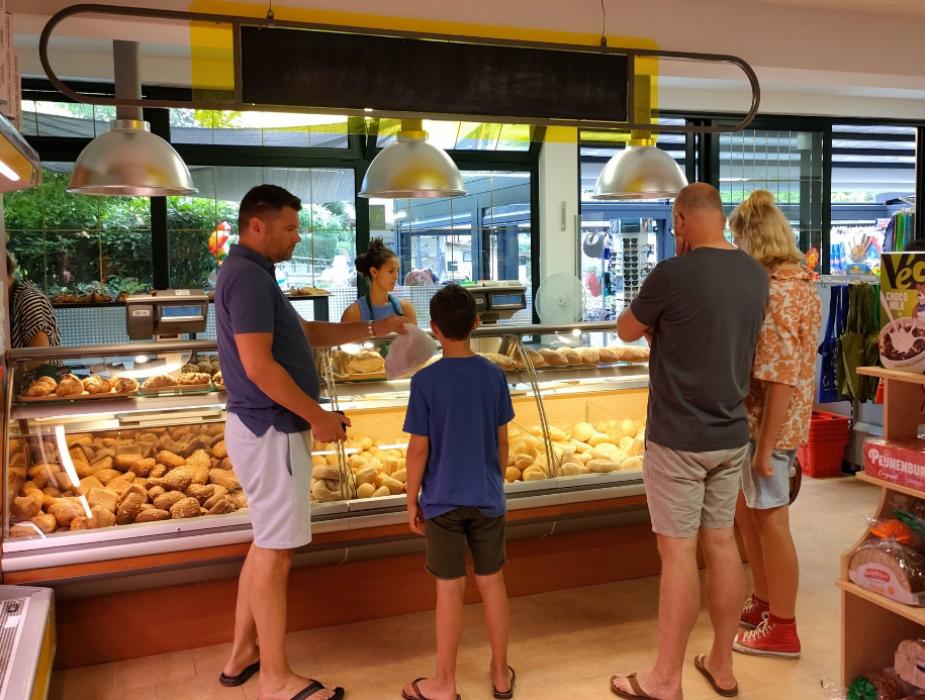 Supermercato con tavoli all'aperto, fiori di glicine in primo piano.