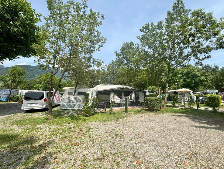 Campeggio con roulotte, auto e alberi in una giornata soleggiata.