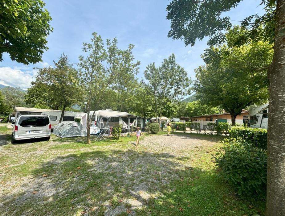 Campeggio con roulotte, tende, alberi e persone che si rilassano all'aperto.