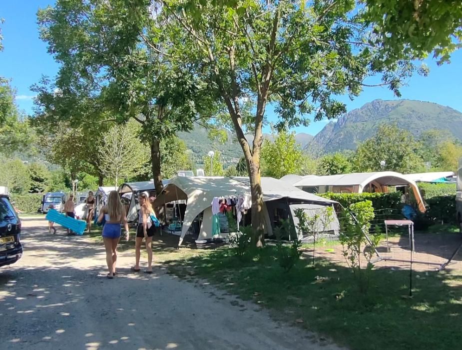 Bambini giocano in campeggio, circondati da camper e natura.