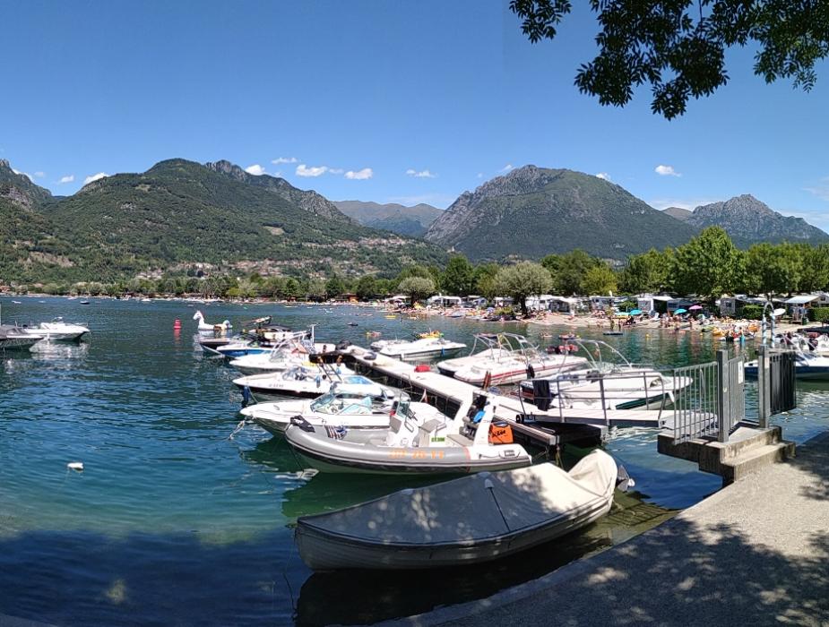 Barche ormeggiate su un lago circondato da montagne verdi e cielo sereno.