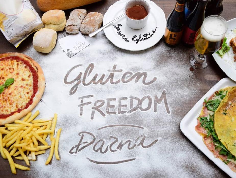 Cibi senza glutine: pizza, pane, birra, dolci, con scritta 'Gluten Freedom'.