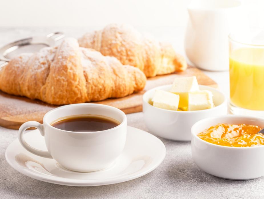 Colazione con caffè, croissant, succo d'arancia, burro e marmellata.