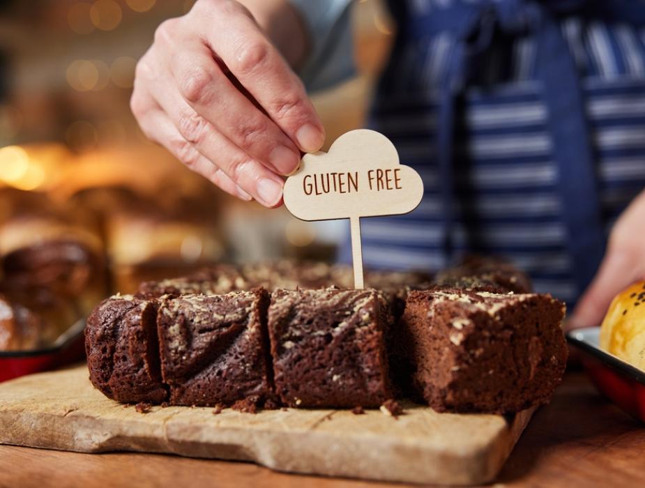 Fetta di torta al cioccolato con etichetta senza glutine su tagliere di legno.