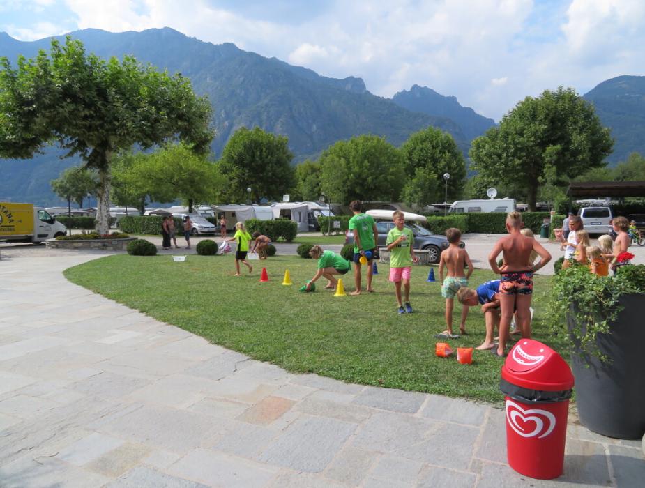 Bambini giocano all'aperto in un campeggio con montagne sullo sfondo.