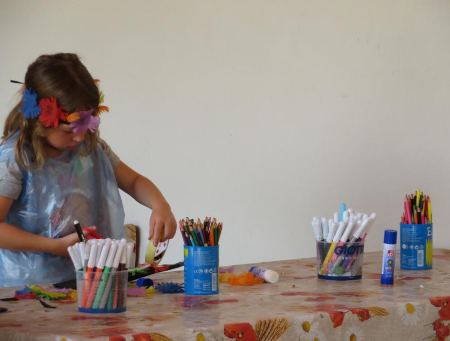 Bambina crea con pennarelli e fiori su un tavolo decorato.