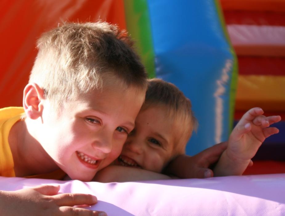 Due bambini sorridenti giocano su un gonfiabile colorato.