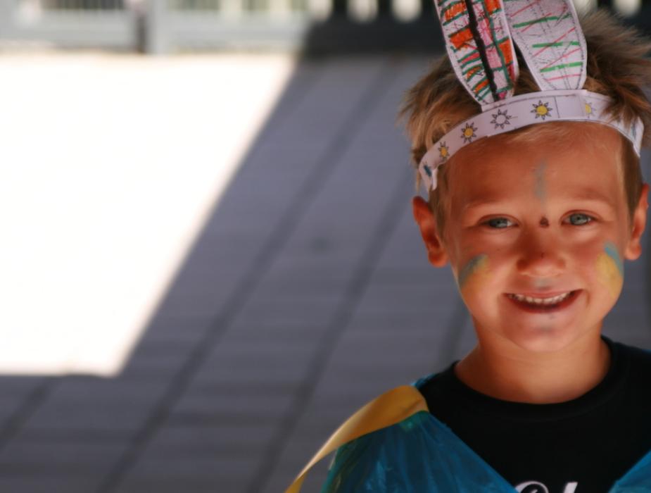 Bambino sorridente con orecchie di carta e pittura facciale colorata.