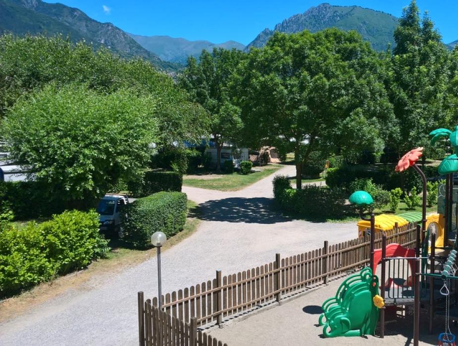 Parco giochi colorato in un'area verde con montagne sullo sfondo.
